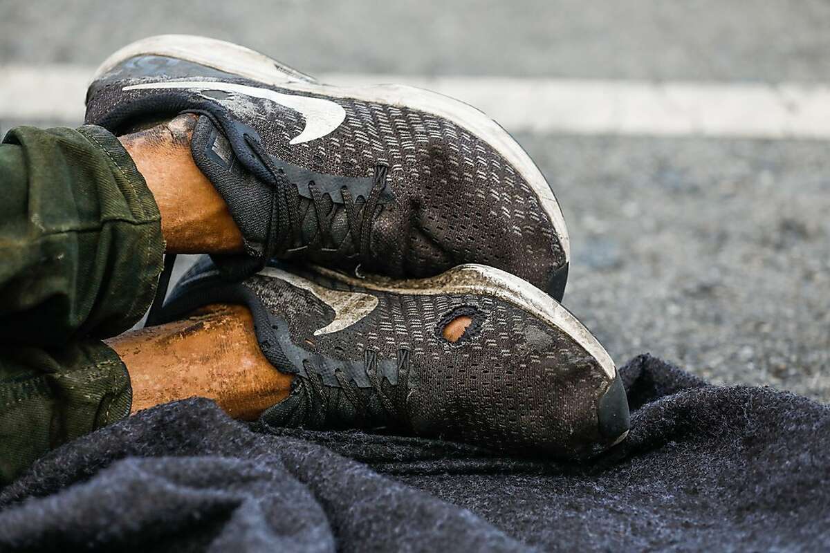 Homeless man Kevin Christopher Highfield's, 39, shoes are seen as he tries to rest in a parking spot on Larkin Street in San Francisco, California, on Tuesday, June 18, 2019. Kevin said he has been homeless since he was 18 years old after getting kicked out of the house by his mother. He broke his left leg and it never properly healed so it causes him great pain. Photo taken on Larkin Street between McAllister and Fulton Streets at 7:08pm