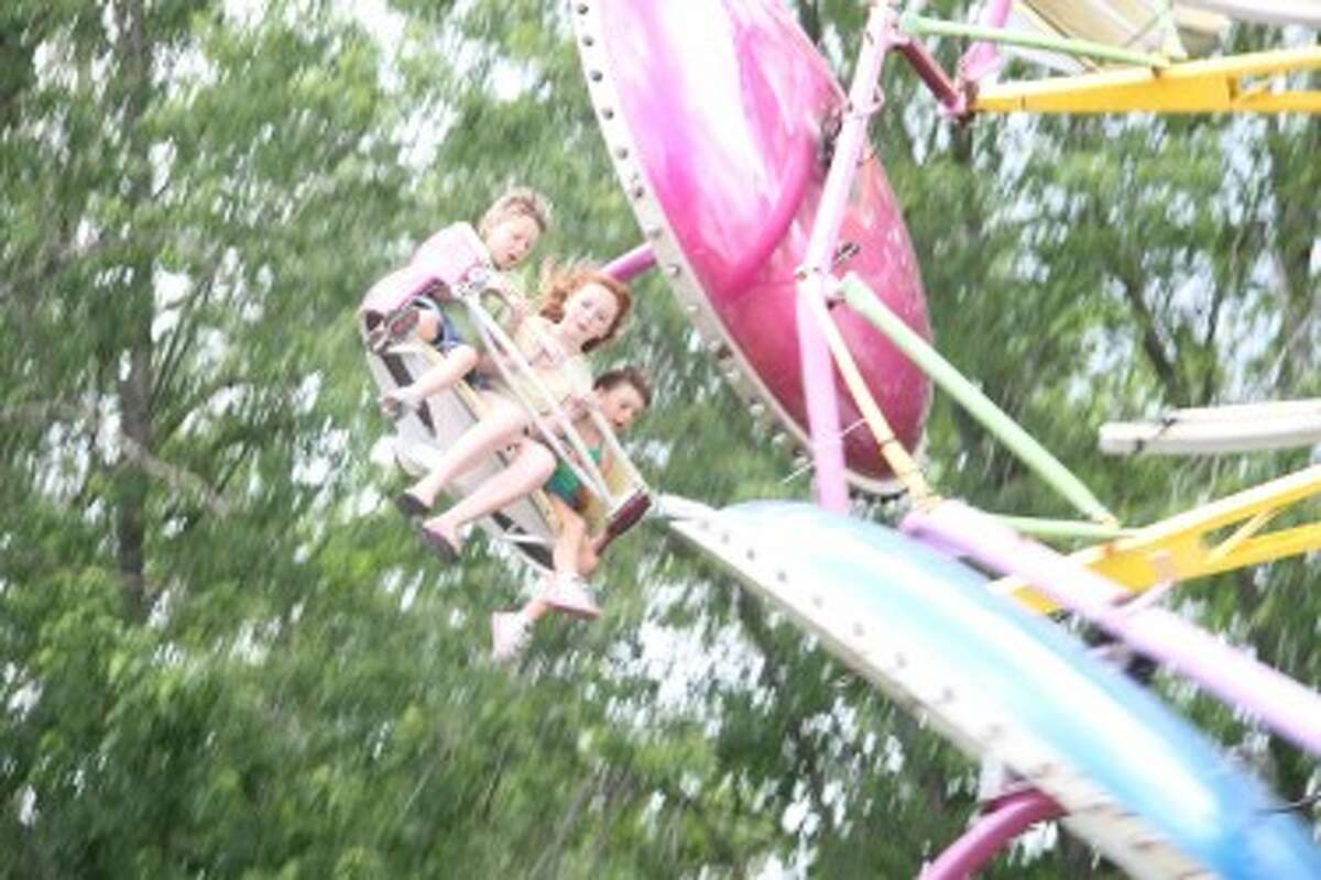 Three children enjoy riding one of the many midway attractions at last year’s Marion Fair. This year, rides, grandstand events and much more will take place from Sunday through June 29 in the village. (Herald Review file photo)