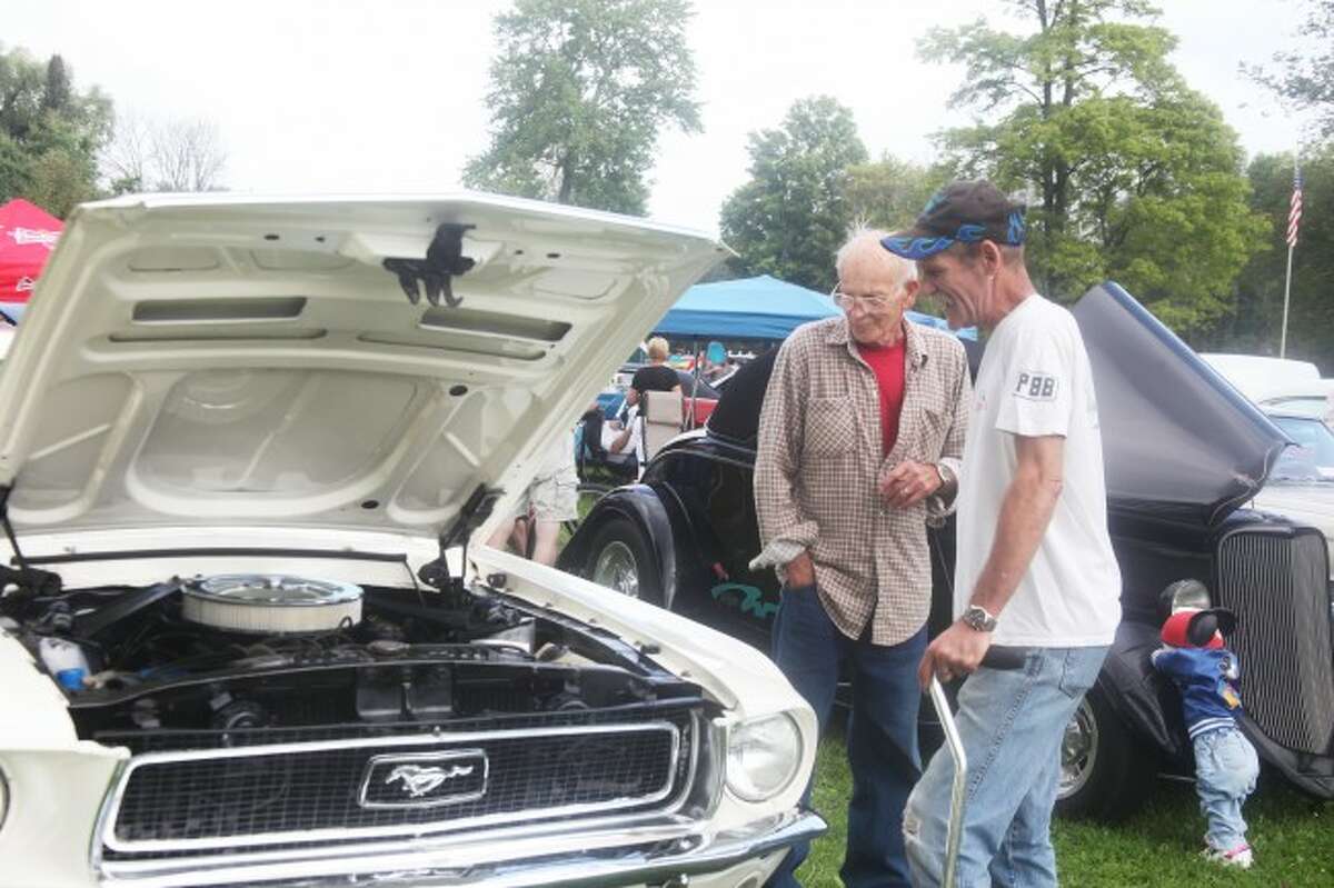 UNDER THE HOOD: Forrest Scott, left, and John Vangardere, right, look at a 1968 Ford Mustang. The two left their cars at home this year, but have been attending the show for many years.