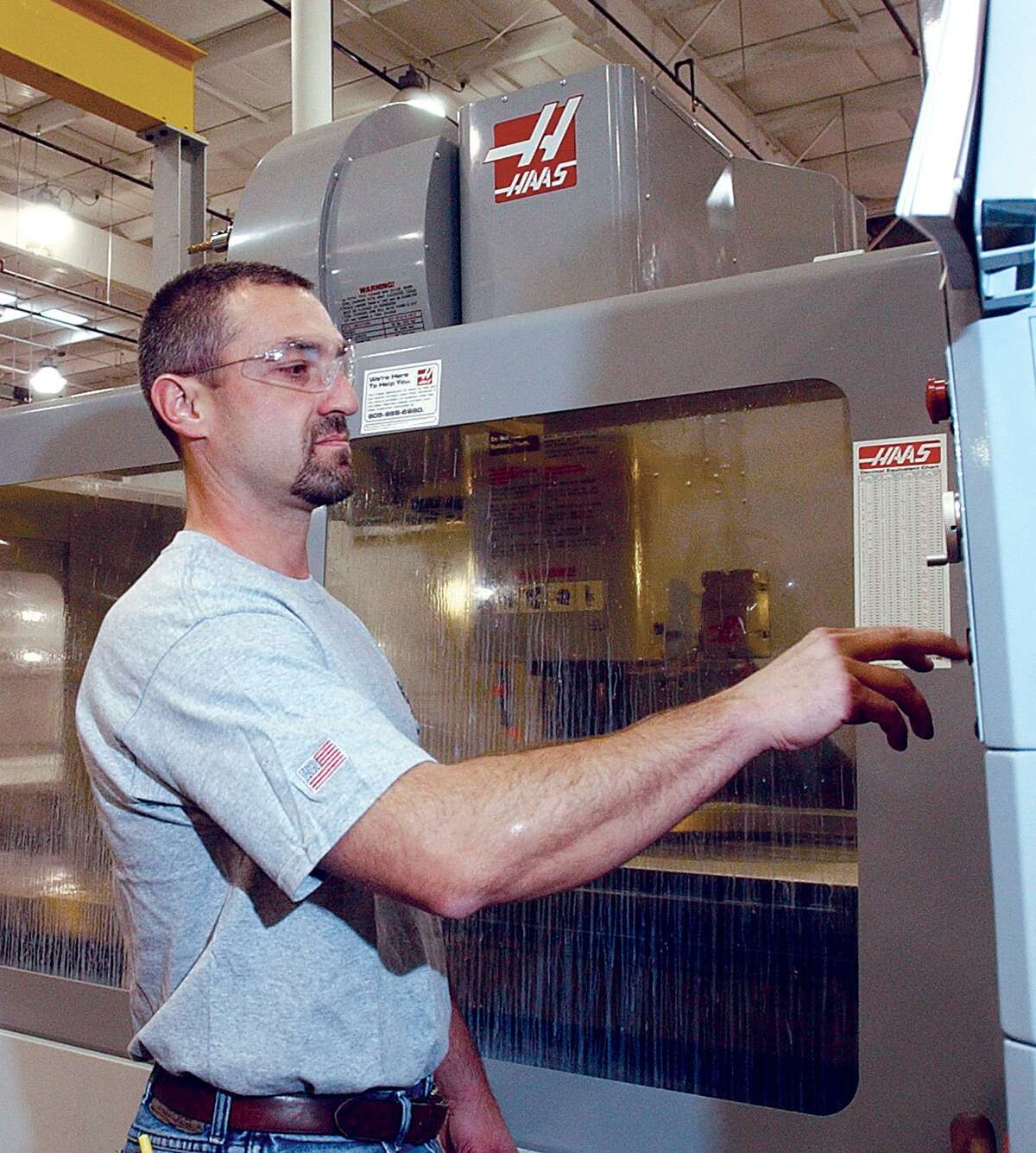 A machining supervisor programs a vertical machining center at the Middletown aerospace manufacturer Pegasus Manufacturing Corp.