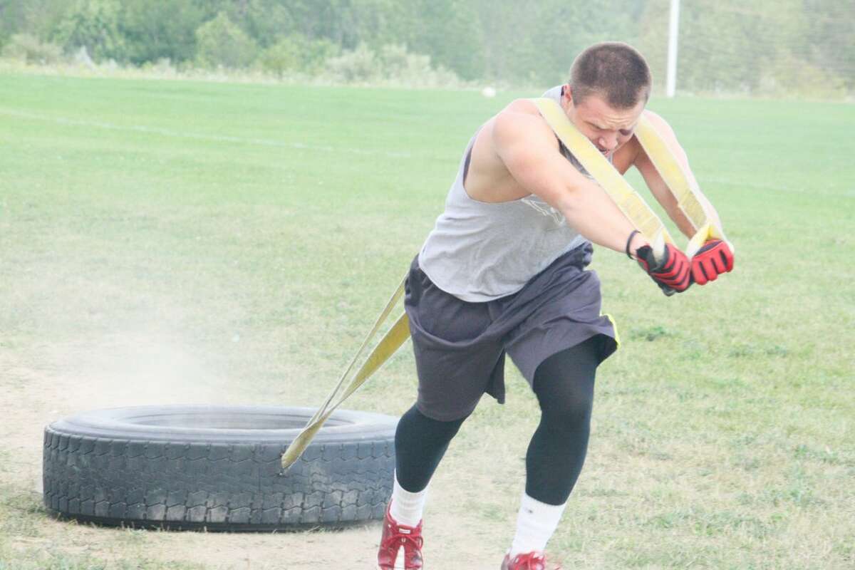 strength training: Garrett Benson of Reed City, getting ready to play football at Alma, works on the tire pull Monday night. (Herald Review/John Raffel)