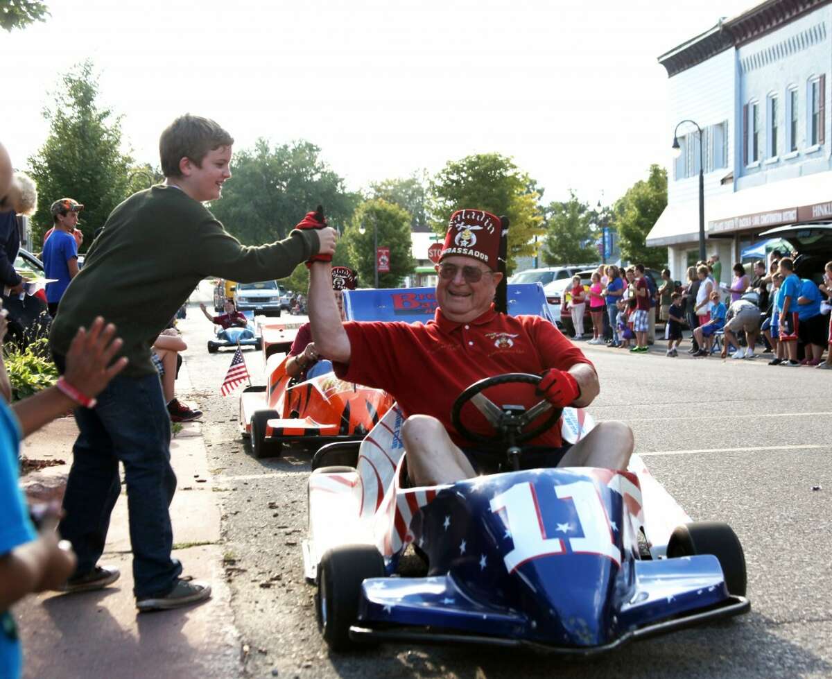 COMMUNITY CROSSROADS: Colby Perez (left) reaches out to a Shriner in the Crossroads Celebration parade in Reed City on Friday.