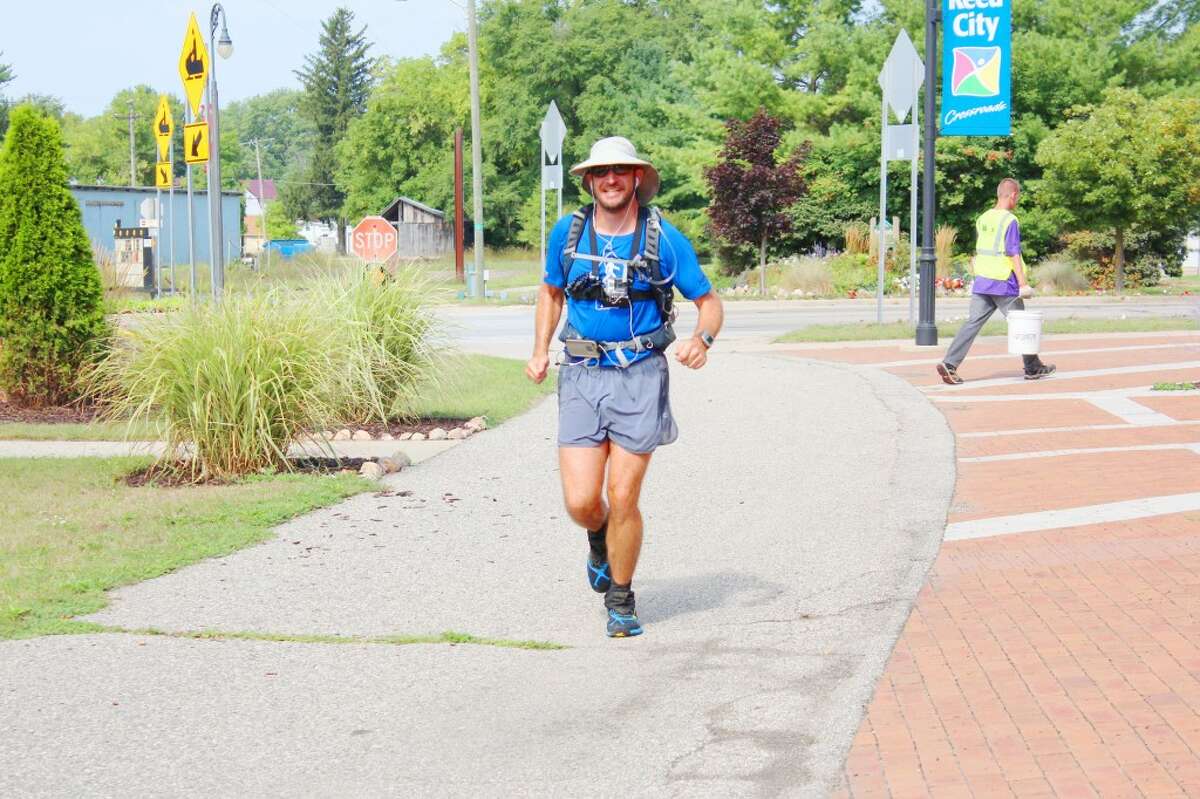 Across the Country: Tuscon native Brian Stark, 41, runs along the Pere Marquette Trail in Reed City on Thursday to reach a break point at the Reed City Depot. Stark has been running across Wisconsin and Michigan to further reach his goal of running through all 50 states. After staying the night in Baldwin, he continued onward through Lake and Osceola counties. His ending point will be in Bay City. (Herald Review photo/Karin Armbruster)