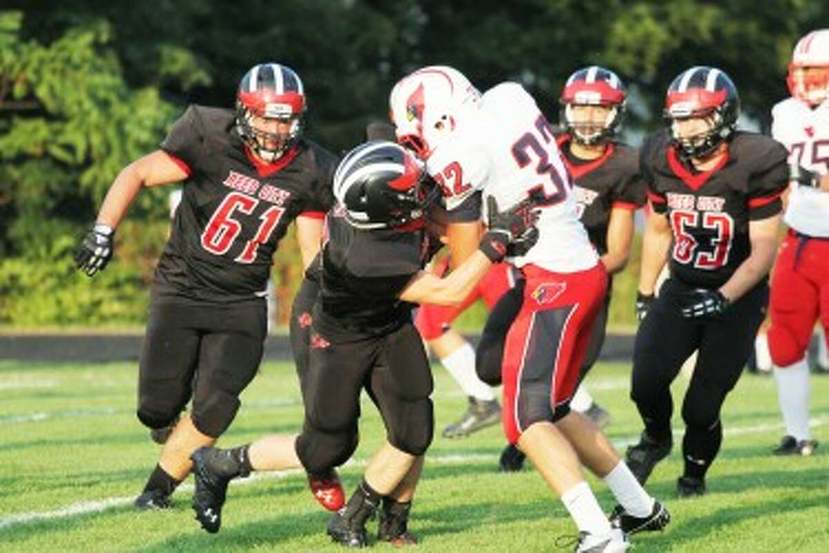 STOUT DEFENSE: Big Rapids running back Jon Spicer (32) is stood up after a short gain while Reed City's Ian MacDonald (61) and Issac Zolman (63) prepare to provide help in the Coyotes' 39-26 win on Friday. (Pioneer photo/Greg Buckner)