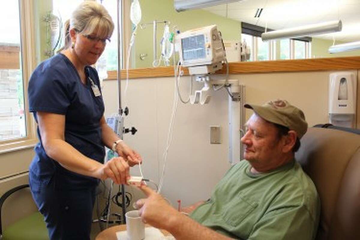 patients: Renee Leonard (left), a nurse at the Susan P. Wheatlake Regional Cancer Center, assists patient Gary Clementshaw, of Reed City, as he receives infusion therapy. Clementshaw said the staff and nurses at the facility are kind and helpful to each patient who walks through the building door. (Herald Review photo/Karin Armbruster)