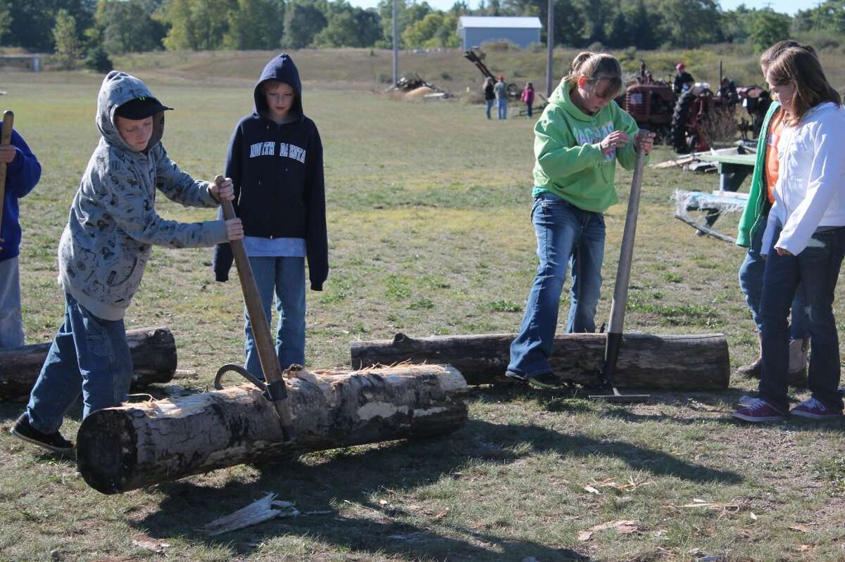 BACK IN TIME: Fifth graders from Reed City Area Schools took a trip to the Big Rapids Antique Farm and Power Club to learn how much work was involved to do things without the modern technology. Here, students find that moving logs with hooks is a lot of hard work. (Herald Review photo/Shannon Hartley)