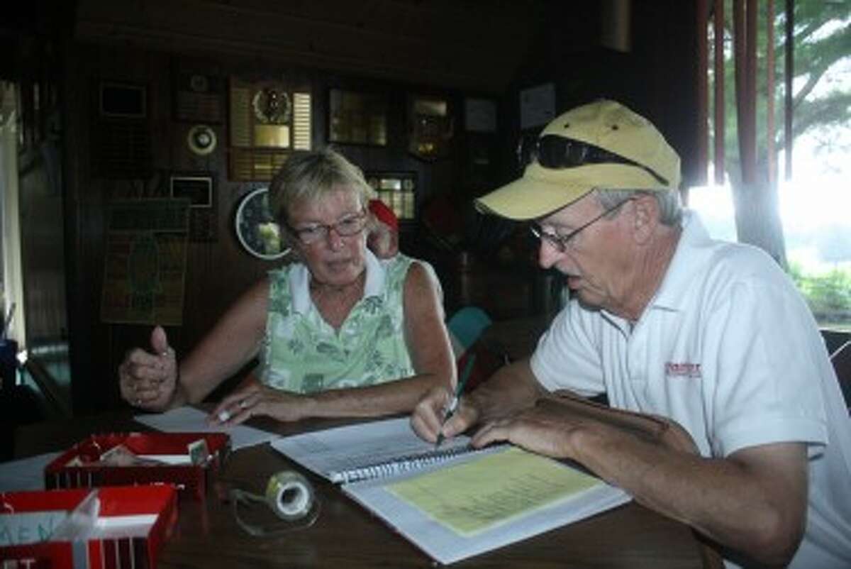DOTTED LINE: Rex Knuth and Sharon McGreehan go over the paperwork Sunday prior to the start of the Mixed Scramble league at Spring Valley. (Pioneer photo/John Raffel)
