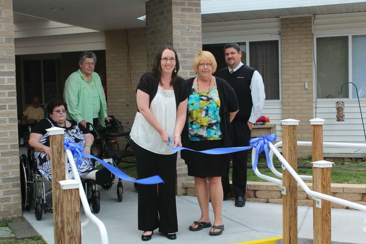 NEW FACILITY: Reed City Housing Commission Board President Kristina Hulliberger cuts a ribbon showcasing the completion og Meadowview Village’s $150,000 renovation project. The project included renovation of the main entrance to the senior building, the addition of sidewalks off the lobby area, a new pavillion, two smoke shelters and an extensive drainage project on the building. (Herald Review photos/Sarah Neubecker)