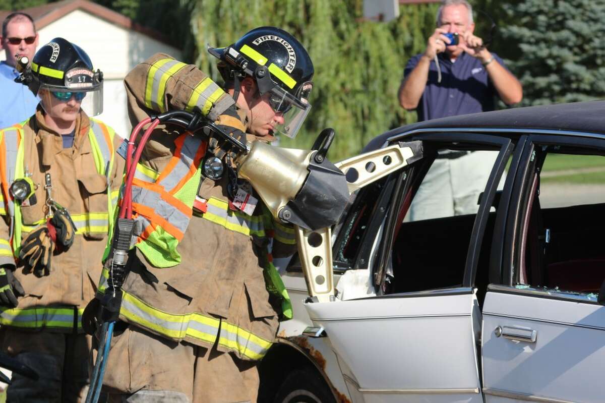 CLEAN CUT: A firefighter from the Reed City Fire Department uses a new hydraulic rescue tool to cut through a donated demo car during a practice exercise Tuesday. The new tools were purchased with a $16,000 AAA grant. (Herald Review photos/Sarah Neubecker)