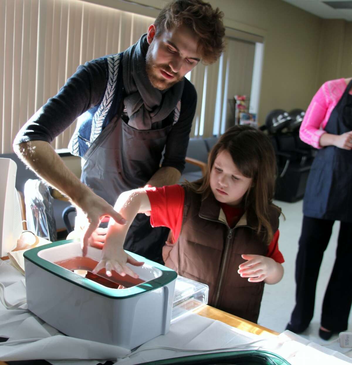 COMMUNITY RESOURCE: Cosmetology student Timothy Sheffer guides Morgan Horvath, 7, through a wax dip at the MOCC open house.