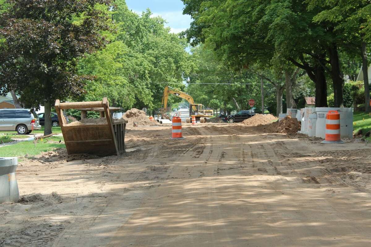 SHAPING CURBS: A curb machine shapes wet concrete to form 6-inch deep curbs on Aug. 15. After the curbs were installed, homeowners had to wait a week to use their driveway.
