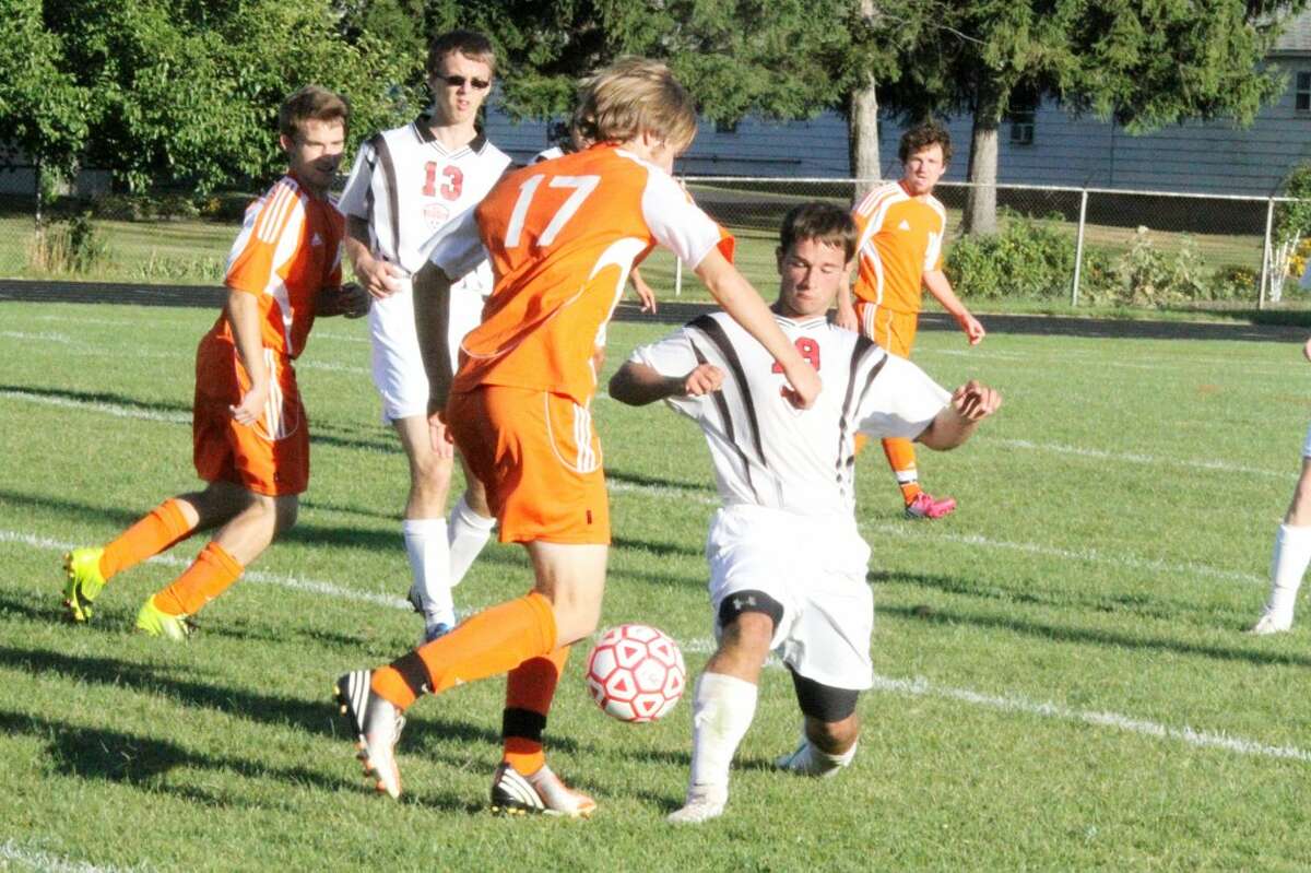 AGGRESSIVE: Reed City's Corey Saladin (right) pokes the ball away from Ludington's Carlyle Petersen (17) during Monday's soccer match at Reed City High School. (Herald Review photo/Martin Slagter)