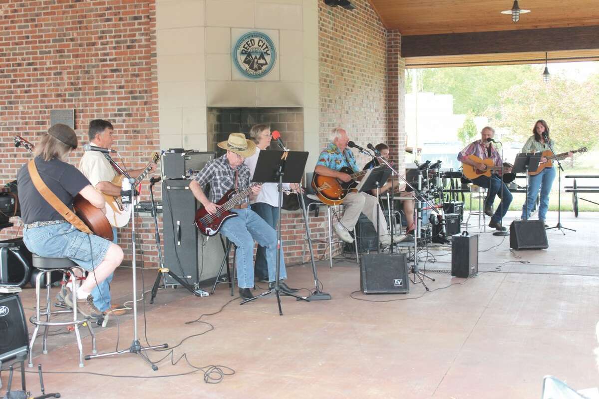 DEPOT CREW: Ron Ouderkirk, center, leads a group of local musicians in serenading crowds at the Reed City Depot. The group plays music ranging from old gospel hymns to new rock favorites. (Herald Review file photo)