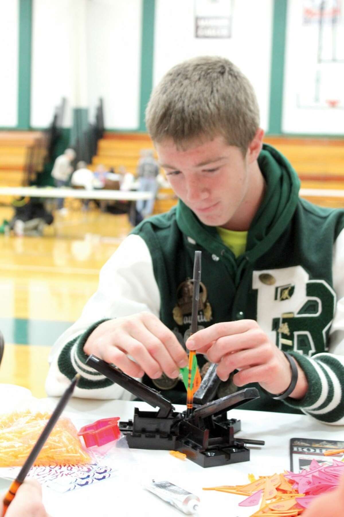 ARROW MAKING: Pine River High School senior Maverick Martin makes an arrow with a ball-point pen and feathers. Students put super glue on the arrows and pressed them together for 30 seconds. (Herald Review photo/Sarah Neubecker)