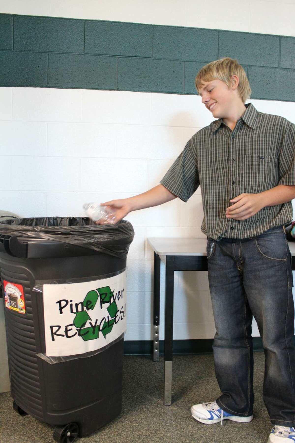 PINE RIVER RECYCLES: Brian Hutchinson, eighth grader at Pine River Middle School recycles a water bottle in one of the school’s recycling bins. Pine River High School joined the middle school in the green initiative this year. (Herald Review photo/Sarah Neubecker)