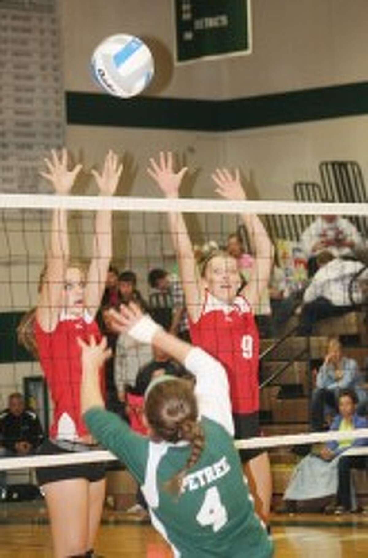 AT THE NET: Reed City's Heather Tacey and Natalie Westhoff try to stop an attack from Clare's Ashley Petree. (Pioneer photo/John Raffel)