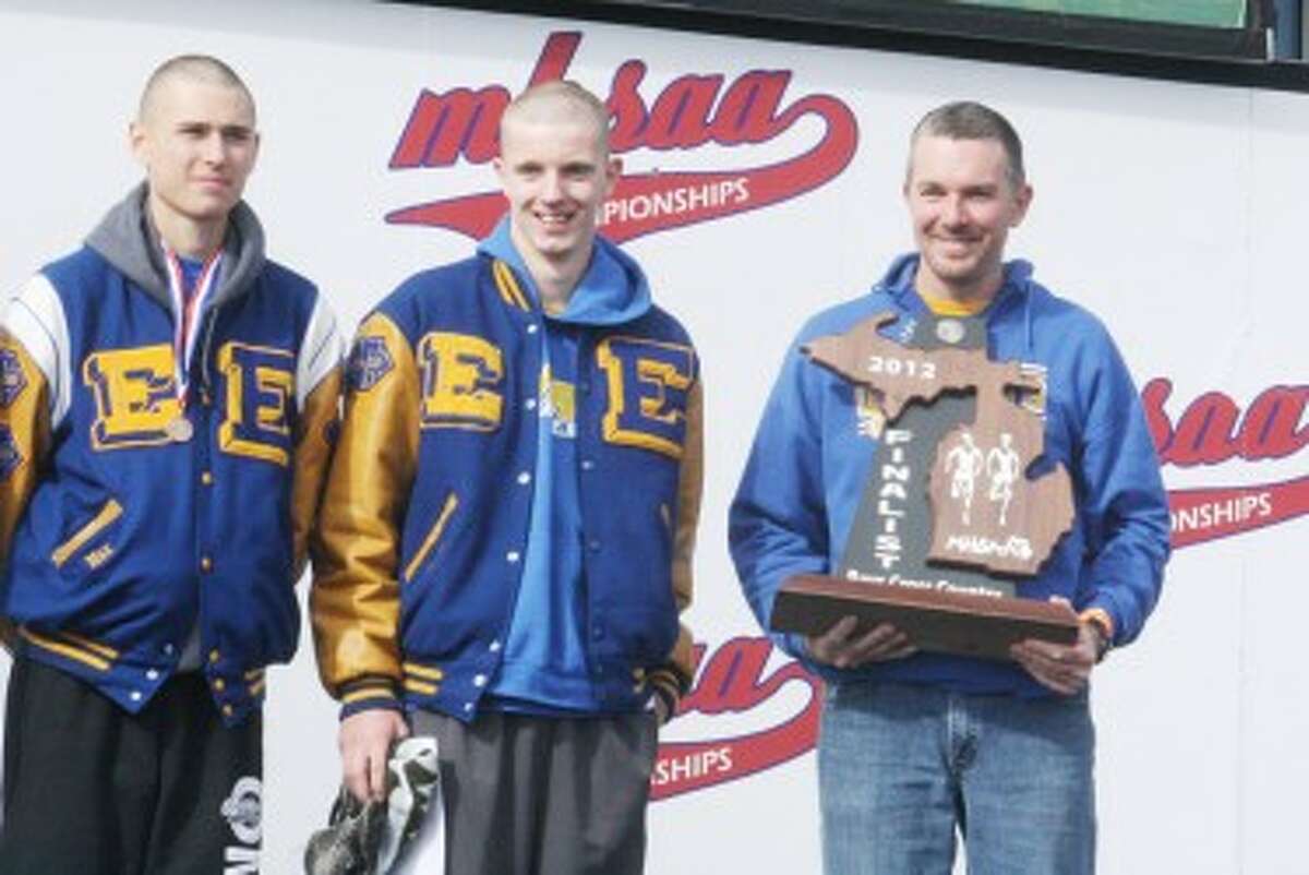 SPECIAL MOMENT: Evart cross country coach Andy Eichelberger holds the Division 4 state runner-up trophy Saturday while Max Hodges (left) and David Zinger enjoy the moment. (Herald Review photo/John Raffel)