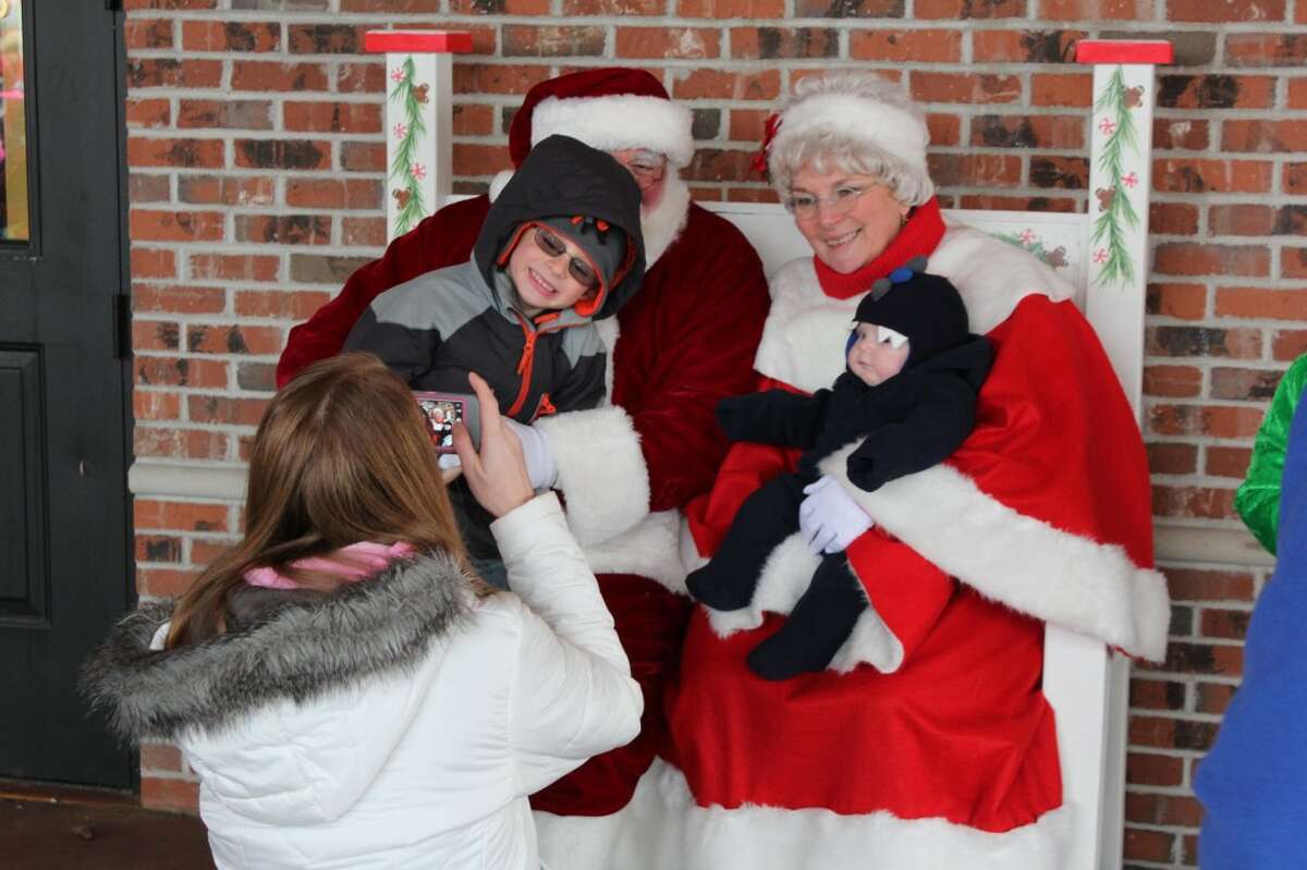 PICTURES WITH SANTA: Nicole Quinn takes a photo of her sons Hunter,4, and Johnny, 3 months, at the Evergreen Festival in Reed City on Saturday. The festival included a parade, craft show and gingerbread cookie-decorating. (Herald Review photos/Sarah Neubecker)