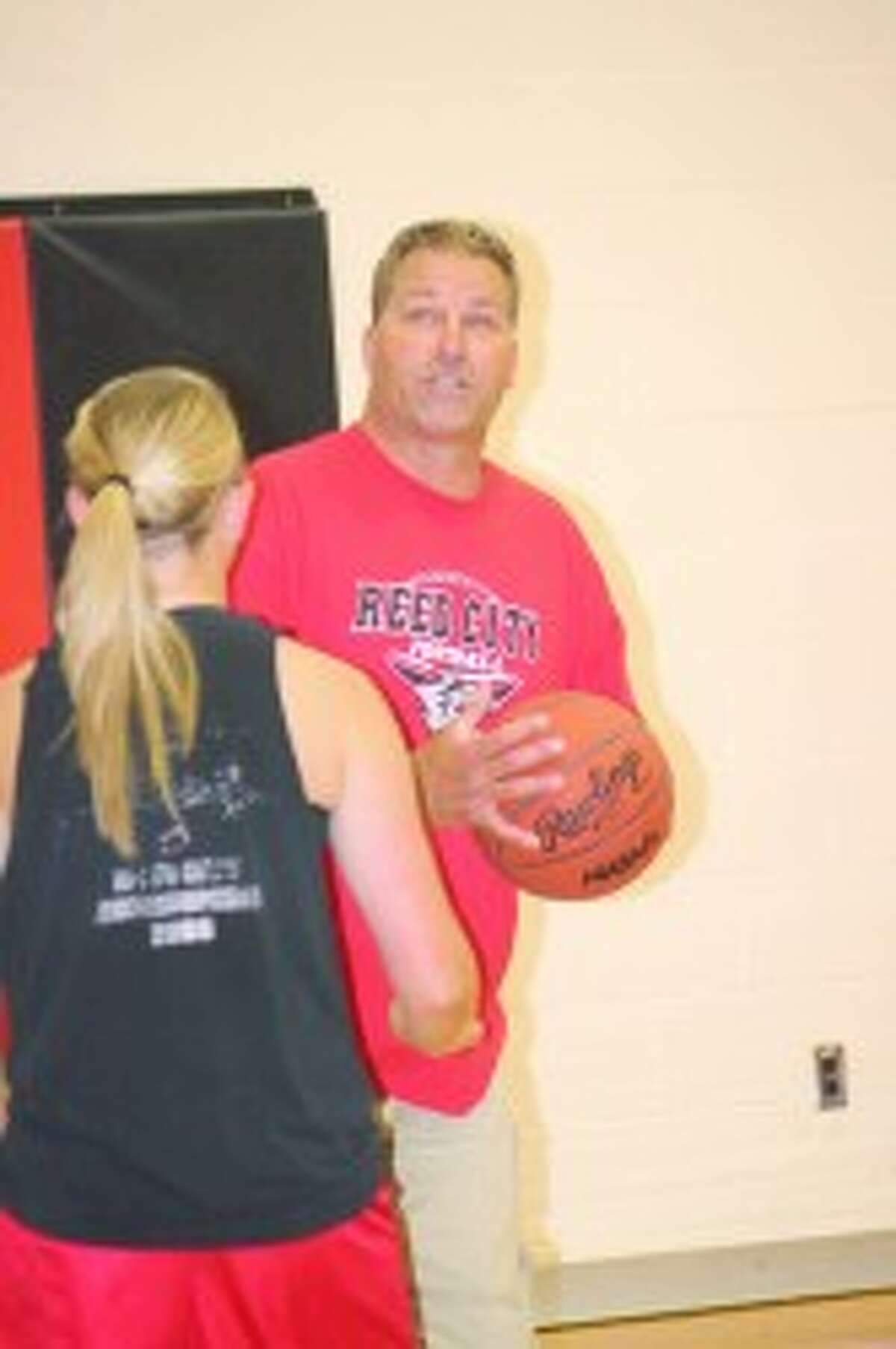 TEACHING MOMENT: Brian Koopman, Reed City girls basketball head coach, works with the team during a recent practice.
