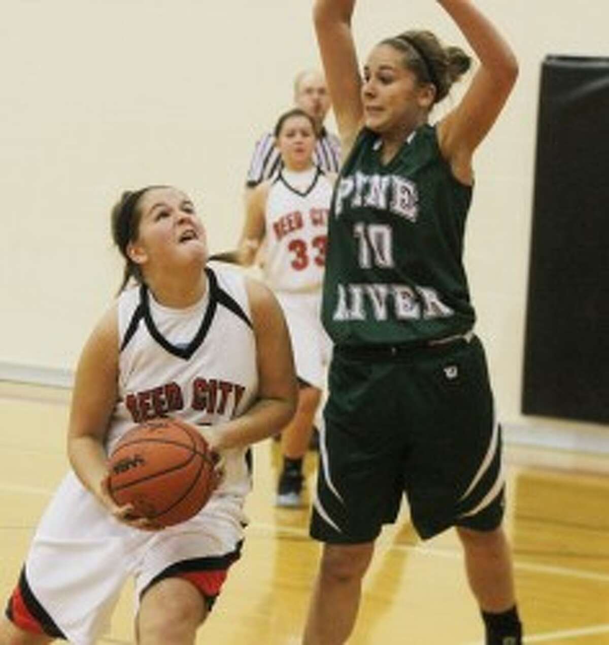 UP AND UNDER: Reed City's Karah Hensel goes up for a shot against Pine River's Kassy Nelson in her team's 62-40 win over the Bucks. (Pioneer photo/Martin Slagter)