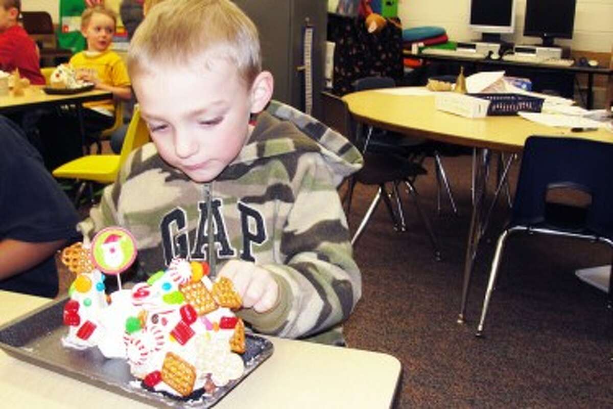 Something tasty: Travis Eisenga from Mrs. Amy Posey’s class is in full concentration as he finishes his creation complete with a Gingerbread Man running up the side of his house.