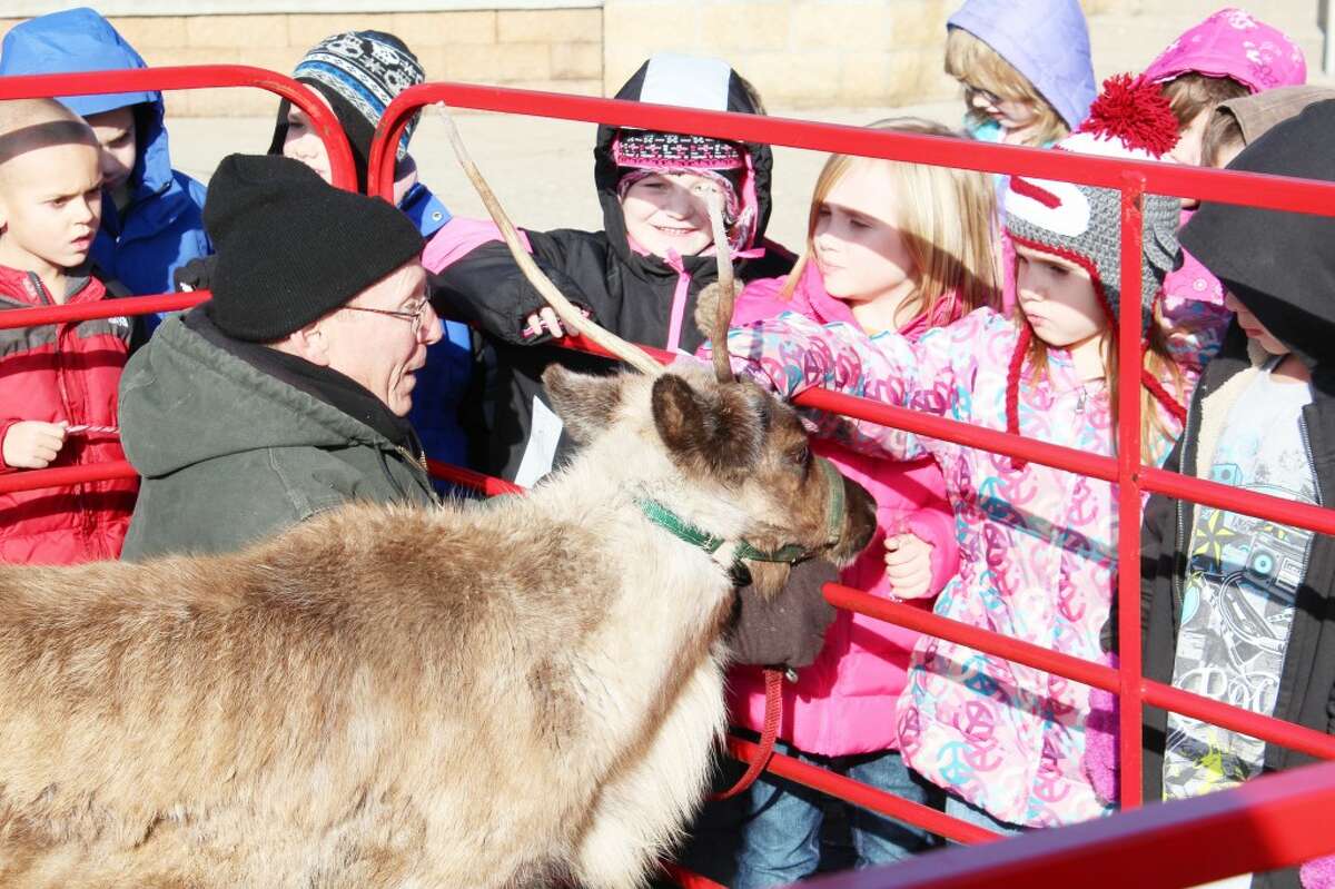 FURRY VISITOR: First-grade students from Evart Elementary School pet Little Prancer, an eight-month-old reindeer from Rooftop Landing Reindeer Farm in Clare. The reindeer visited the students on Dec. 19. (Herald Review photos/Sarah Neubecker)