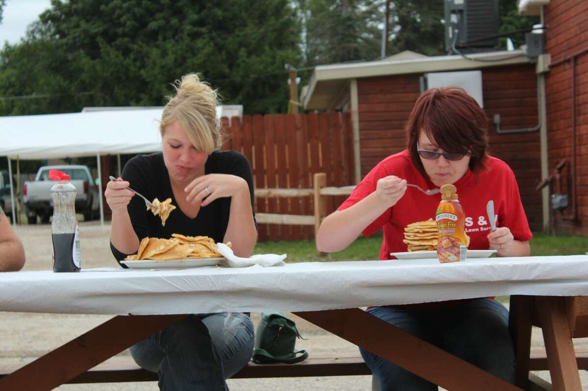 HEAD-TO-HEAD: Pioneer intern Emily Grove (left) and Jamie Magnusson(right) compete in the inaugural Pancake Eating Contest at the Hersey RIver Town Festival on Saturday.