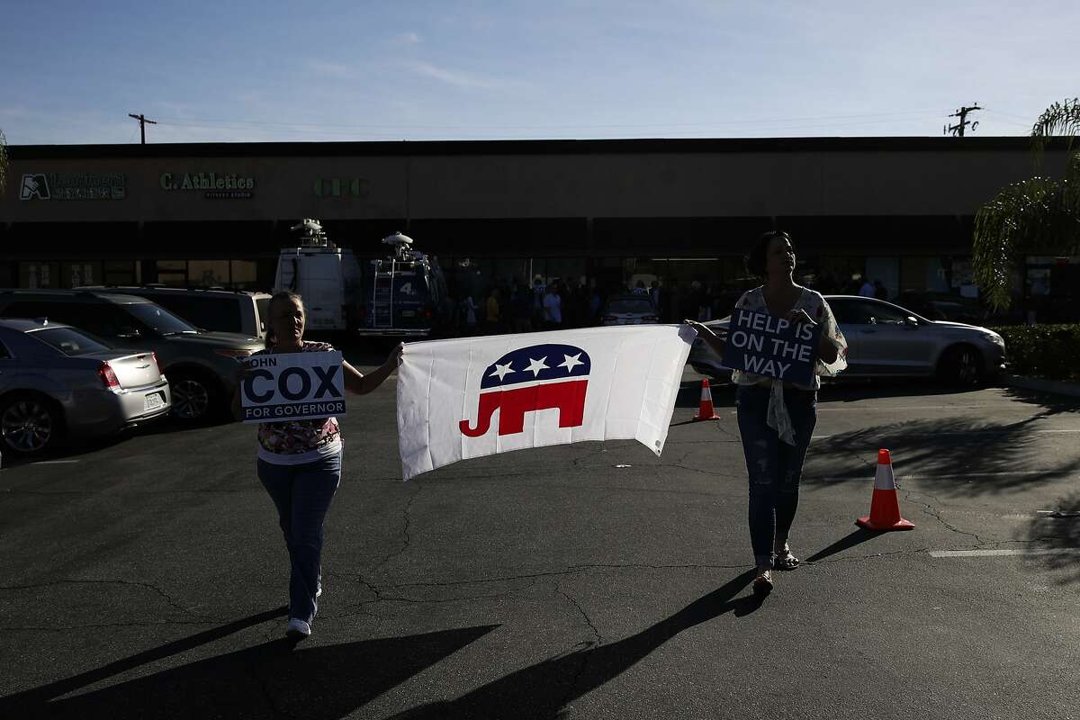 Two supporters carry a flag made with the elephant symbol of the Republican party while waiting for the arrival of gubernatorial candidate John Cox and Young Kim, a candidate running for a U.S. House seat in the 39th District in California, at a campaign stop Saturday, Nov. 3, 2018, in Rowland Heights, Calif. California's gubernatorial candidates target Orange County on Saturday, a place where Democrats hope to turn over four congressional seats. (AP Photo/Jae C. Hong)