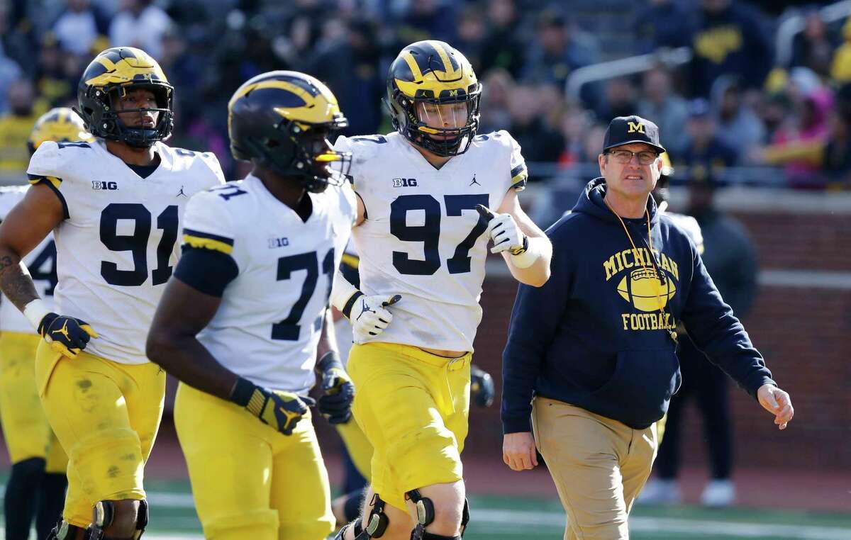 FILE- In an April 13, 2019, file photo, Michigan head coach Jim Harbaugh walks out with players during the team's annual spring NCAA college football game in Ann Arbor, Mich. Harbaugh seems to be set up for success at Michigan in his fifth season, leading a program that is a popular choice to win the Big Ten. "That's where I would pick us," Harbaugh said. Some are predicting the Wolverines will earn a spot in the College Football Playoff to give them a chance to win a national championship for the first time since 1997. (AP Photo/Carlos Osorio, File)