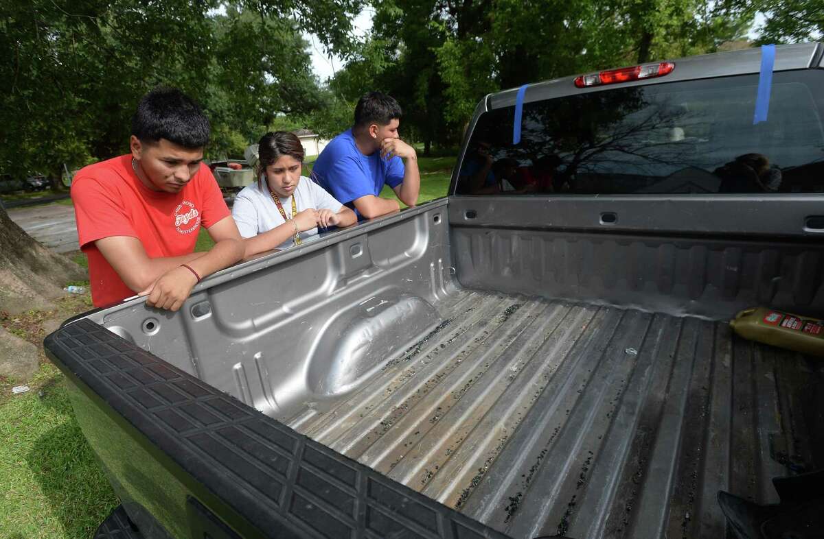 Hosvaldo Rodriguez, 19, (left) and Britney Arvizu stare down into the bed of the truck belonging to Hosvaldo's cousin, Jesse Angel Rodriguez, who was fatally shot Saturday night following an incident at Cicis Pizza near Eastex Freeway. Pieces of broken glass and the tape from rear window replacement remained in the truck bed. Members of the family and friends gathered at the family's home for a taco fundraiser to help with expenses moving forward. Hosvaldo says he and Jesse were very close, attending school together at West Brook and often hanging out and working on renovating cars, and even working together at a local rebar business. Three suspects have now been arrested and charged in the incident. Photo taken Tuesday, August 20, 2019 Kim Brent/The Enterprise