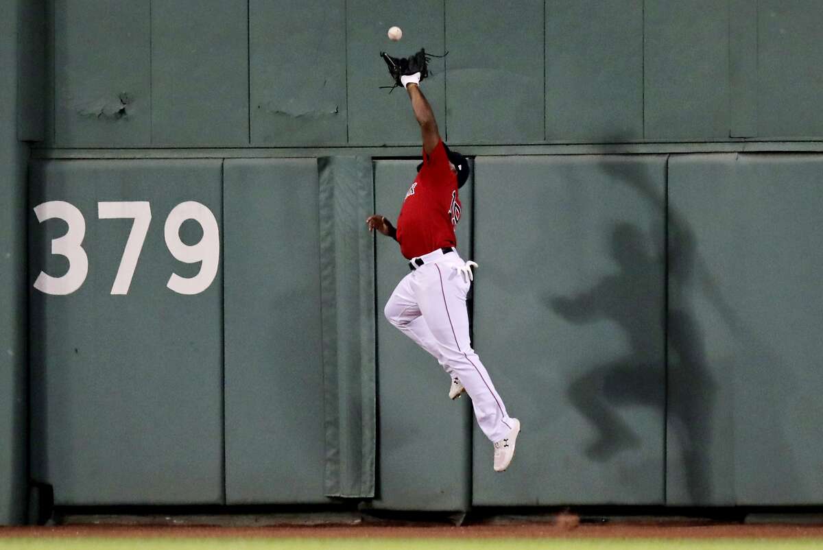 Boston Red Sox's Jackie Bradley Jr. leaps to make the play in deep center field on a fly out by Philadelphia Phillies' Bryce Harper during the eighth inning of a baseball game at Fenway Park in Boston, Tuesday, Aug. 20, 2019. (AP Photo/Charles Krupa)