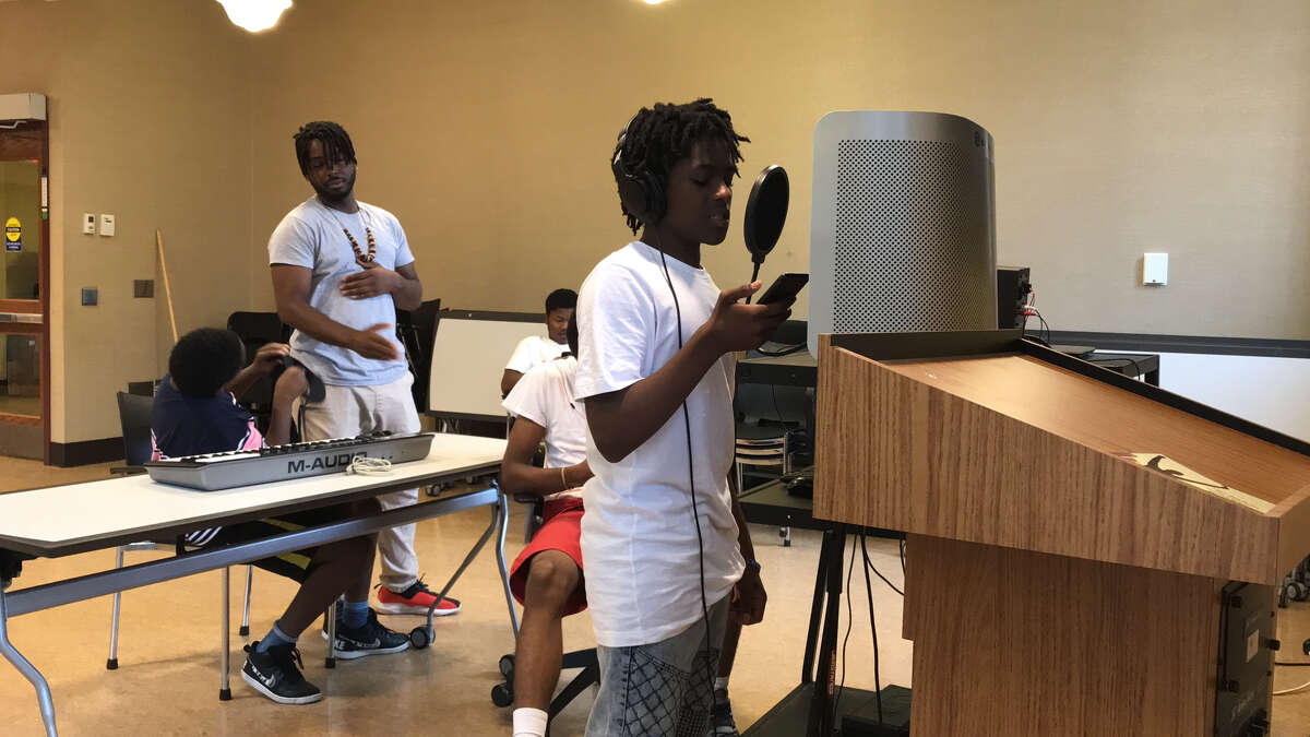 Nykale Burbridge, standing at right, records a rap song in the'Mic Drop' program at Albany Public Library's Howe Branch, overseen by Ozymandias Merci Morris, rear. Seated are Chance Bradford, left, James Kitchen, rear, and Jahleim Holmes, red shorts at right (photo by Amy Biancolli)