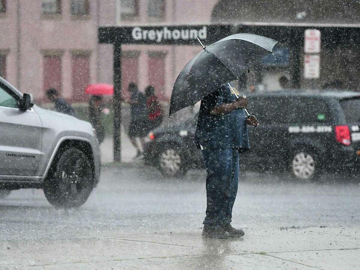 A man stands near the Greyhound bus station with an umbrella during a thunderstorm. (Lori Van Buren/Times Union)