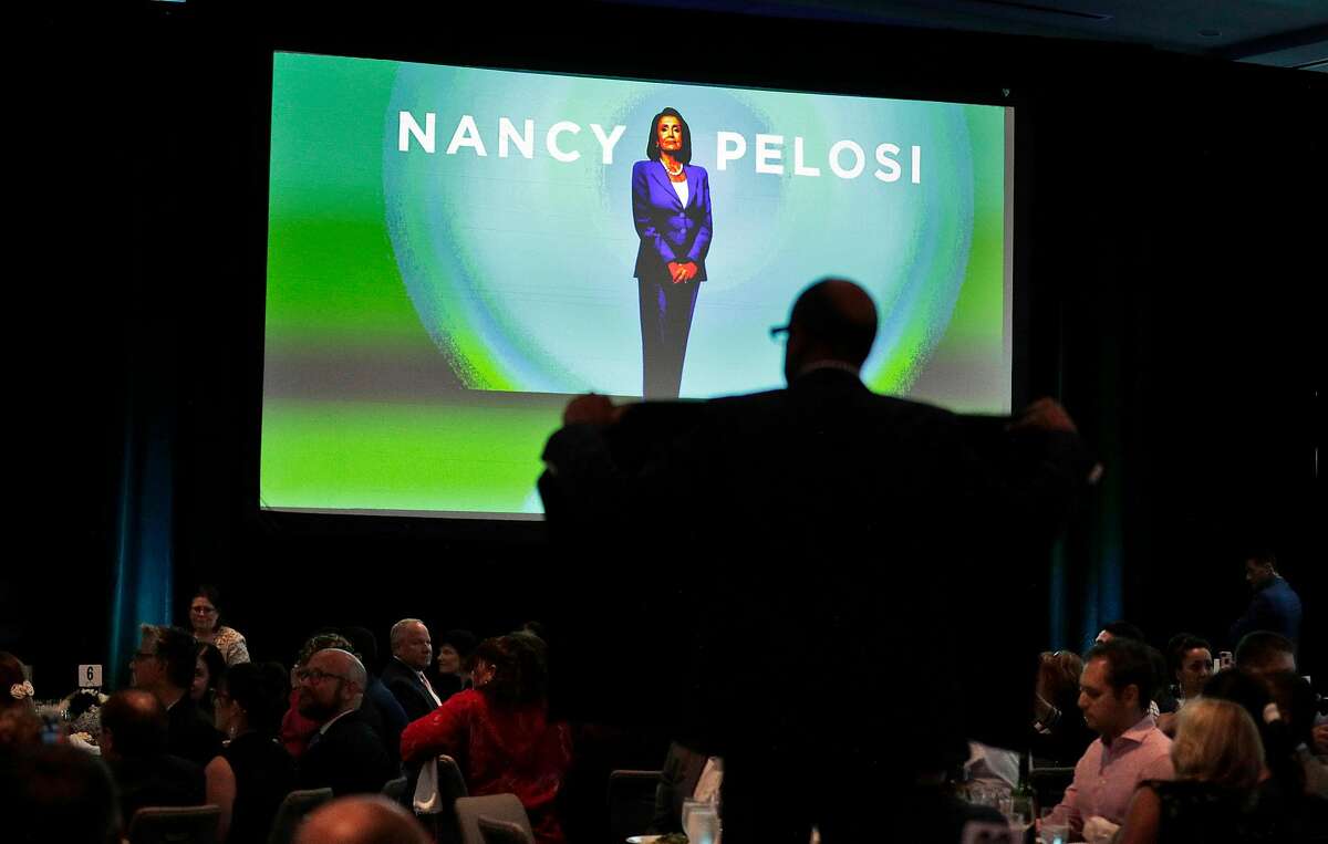 Protester holds a sign in the audience as Nancy Pelosi received a lifetime achievement award from the San Francisco Democratic Party at the Intercontinental Hotel in San Francisco, Calif., on Wednesday, August 21, 2019. There were a large number of groups picketing outside and several protesters managed to get into the event to urge her to launch impeachment proceedings.