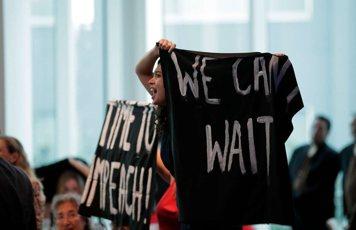 Thais Marques, front, and Karen Fleshman, rear. with Credo, yell and holds banner reading, "We Can't Wait," and "Time To Impeach!" as Nancy Pelosi received a lifetime achievement award from the San Francisco Democratic Party at the Intercontinental Hotel in San Francisco, Calif., on Wednesday, August 21, 2019. There were a large number of groups picketing outside and several protesters managed to get into the event to urge her to launch impeachment proceedings.