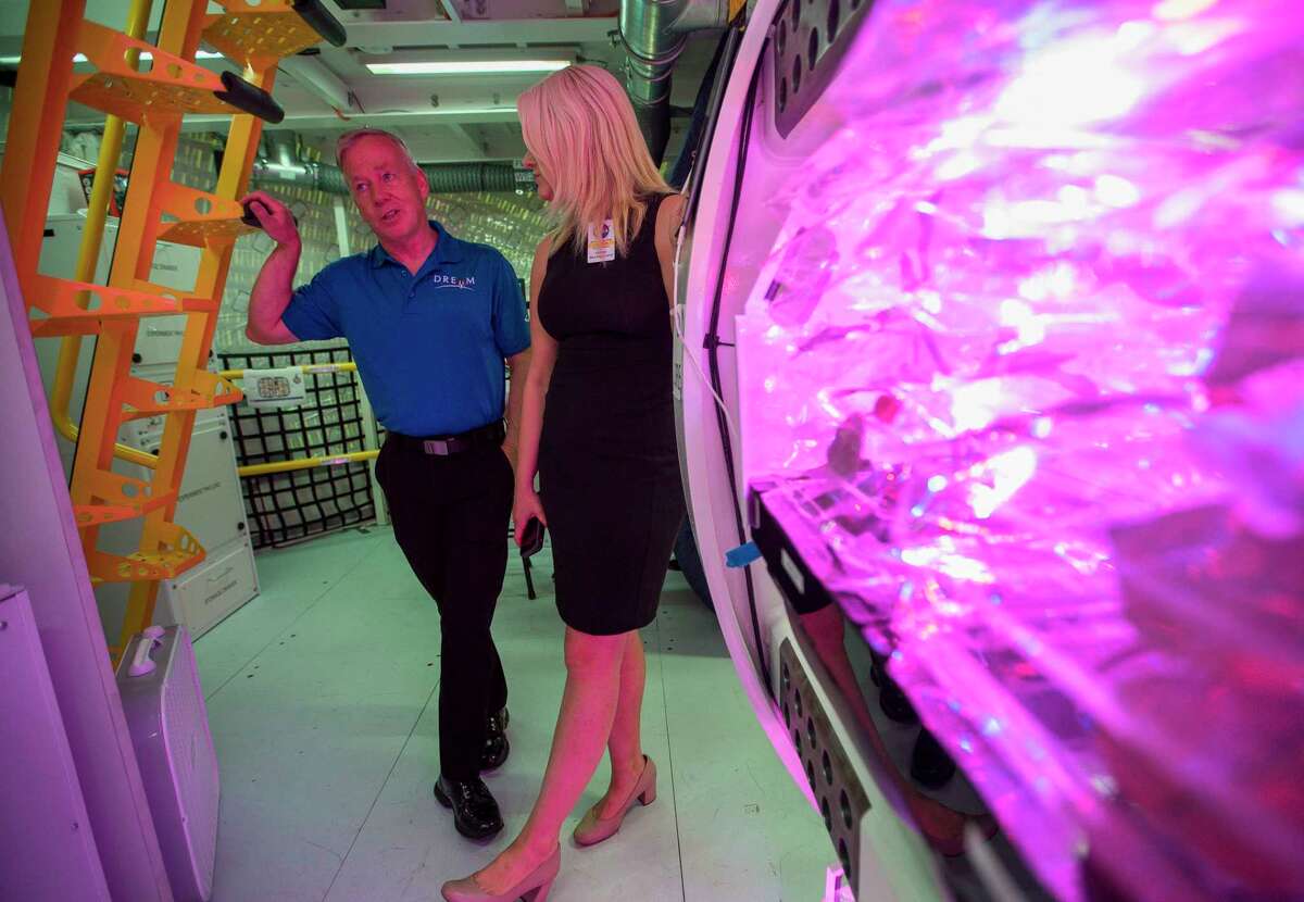 Former NASA astronaut, space shuttle commander and current Sierra Nevada Corporation (SNC) vice president Steve Lindsey leads a tour of SNC's prototype for an inflatable space habitat that could be used for NASA's lunar orbital platform gateway project, during a press event at Johnson Space Center in Houston, Wednesday, Aug. 21, 2019. The purple glow comes from a vegetable growing system on display that SNC designed and is currently operating on the International Space Station. The habitat is designed to fit inside the cargo area of a commercial launch vehicle and then be inflated and outfitted in space. The habitat as currently modeled consists of three floors outfitted for a crew of four astronauts.