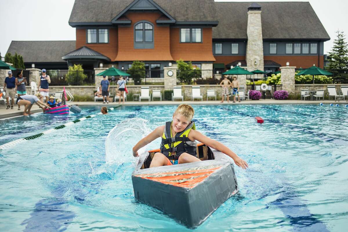 Drew Dittenber, 9, races his boat across the swimming pool at the Midland Country Club during a cardboard regatta Tuesday, Aug. 20, 2019. (Katy Kildee/kkildee@mdn.net)