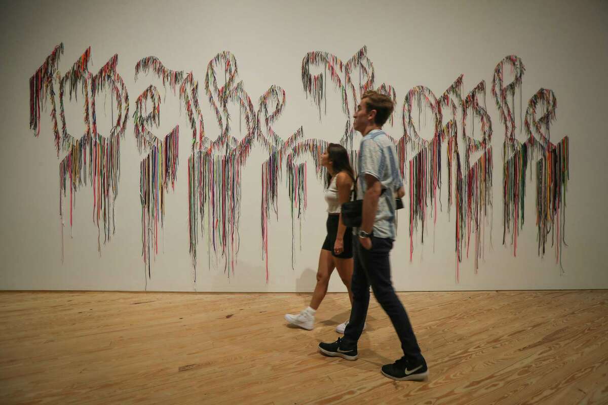 Visitors, Nichole Kury and Jason Amico view Nari Ward: "We the People" at the Contemporary Arts Museum Houston part of a 25-year survey of large-scale sculptures Wednesday, Aug. 21, 2019, in Houston.