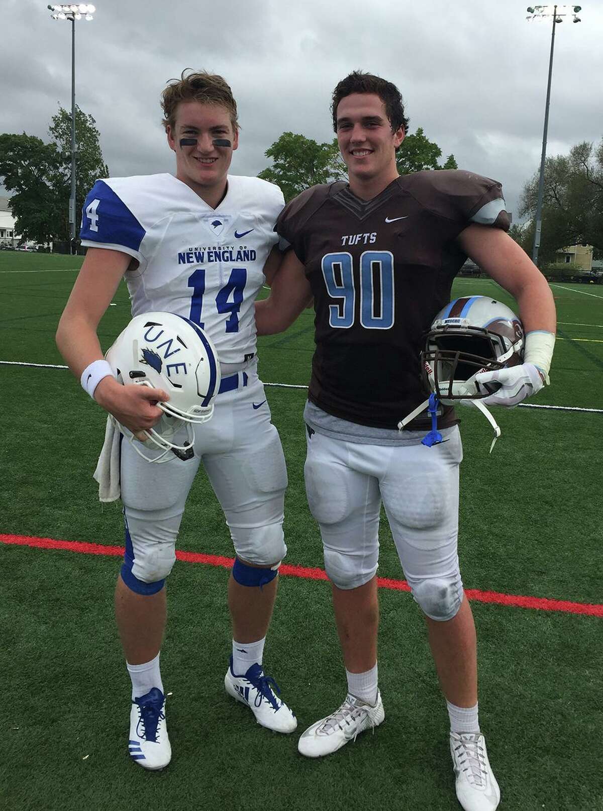 Former Darien teammates Brian Peters (14, left) of the University of New England and Quinn Fay (90) of Tufts University meet on the field during a football game in 2017.