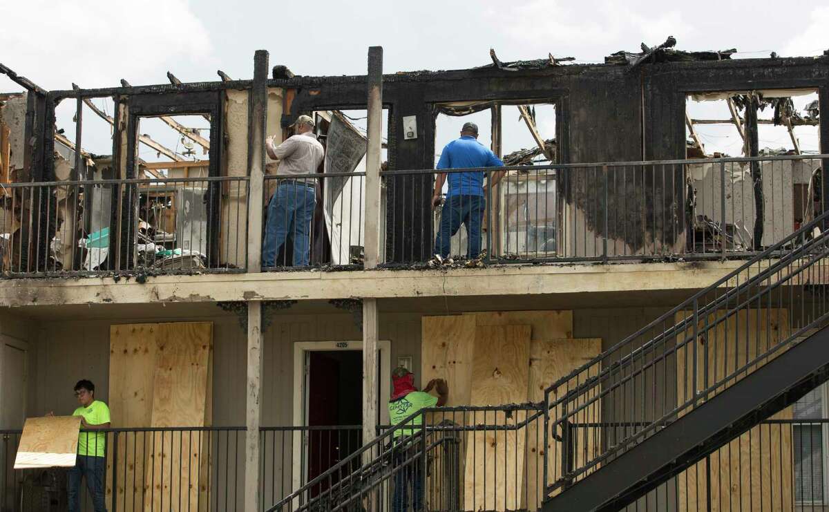 Workers boarding up and assessing a Haverstock Hills Apartments building after an overnight fire that burnt down the third floor of the three-story building on Friday, Aug. 23, 2019, in Houston. The two-alarm fire started before 1 a.m. at the apartment complex located at the 5600 block of Aldine Bender Road, and 27 people were displaced.