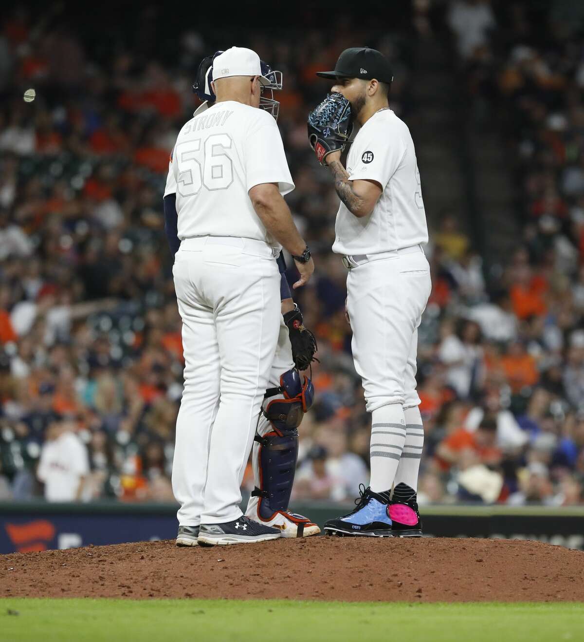 Houston Astros relief pitcher Roberto Osuna (54) talks with pitching coach Brent Strom (56) during the ninth inning of an MLB game at Minute Maid Park, Friday, August 23, 2019.