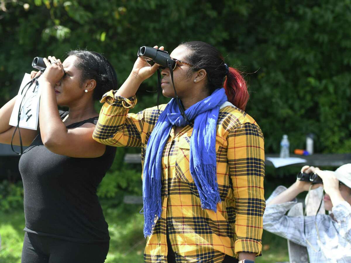 Associated PressStamford's Christina Domond, center, looks at hawks through binoculars at the Hawk Watch Kickoff and Raptor ID Workshop at Audubon Greenwich in Greenwich, Conn. Sunday, Aug. 25, 2019. Audubon naturalist Ryan MacLean kicked off the hawk-watching season by giving helpful tips to identify migrating raptors as attendees used binoculars to see the birds up close.