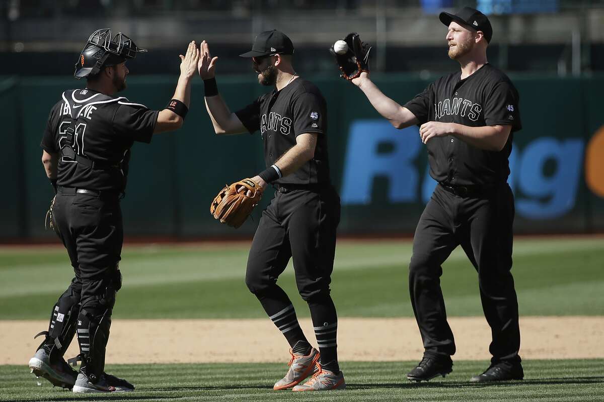San Francisco Giants catcher Stephen Vogt, from left, celebrates with third baseman Evan Longoria and pitcher Will Smith after the Giants defeated the Oakland Athletics in a baseball game in Oakland, Calif., Sunday, Aug. 25, 2019. (AP Photo/Jeff Chiu)