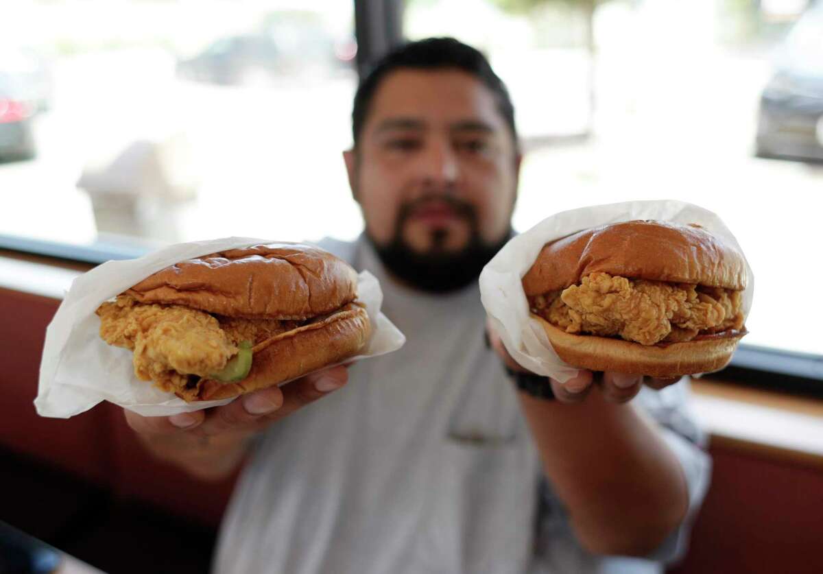 Randy Estrada holds up chicken sandwiches at a Popeyes in Kyle, Texas.