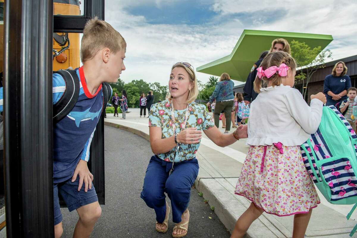 Amy Gladwell Jones, a speech language pathologist at Miller-Driscoll, welcomes students as they get off the school bus on the first day of school on Tuesday.