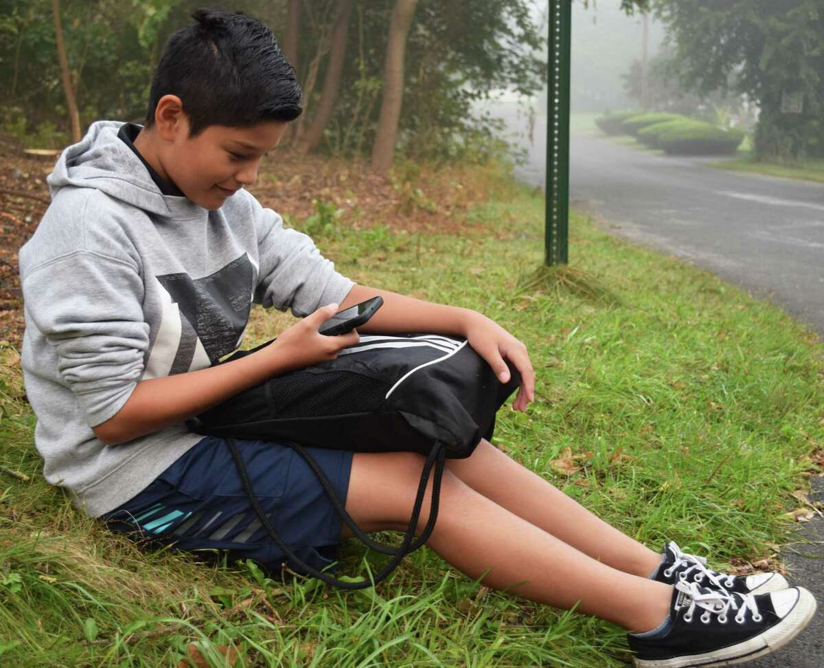 Dylan Nieto checks his phone before hopping on the bus to go to Schaghticoke Middle School for his first year as a sixth grader.
