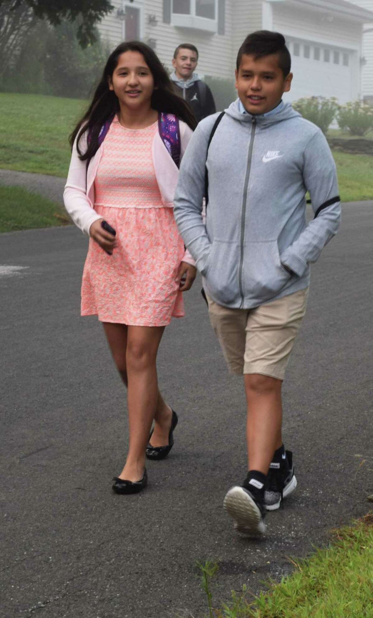Spectrum/New Milford students headed back to school Tuesday, Aug. 27, 2019. Above, siblings Barbara and Peter Cardenas greet friends at their respective bus stops for middle and high school.