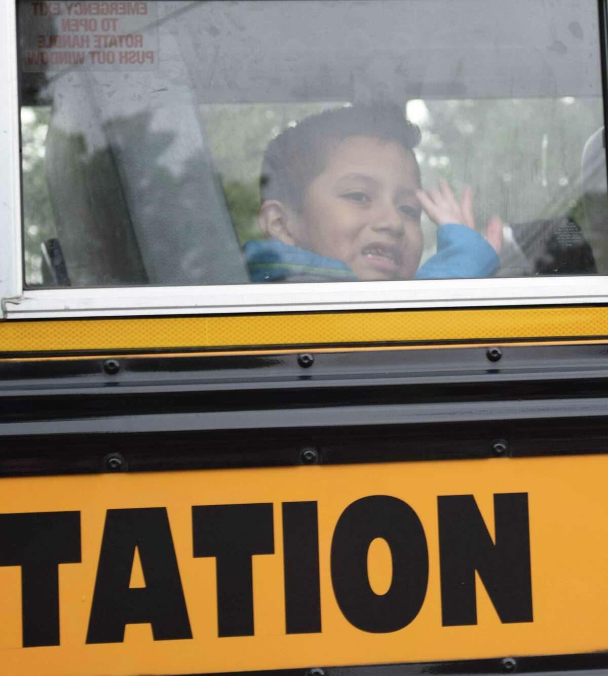 Mateo Bonilla waves goodbye to his mother from his bus window, heading off to his first day of second grade at Hill and Plain Elementary School.