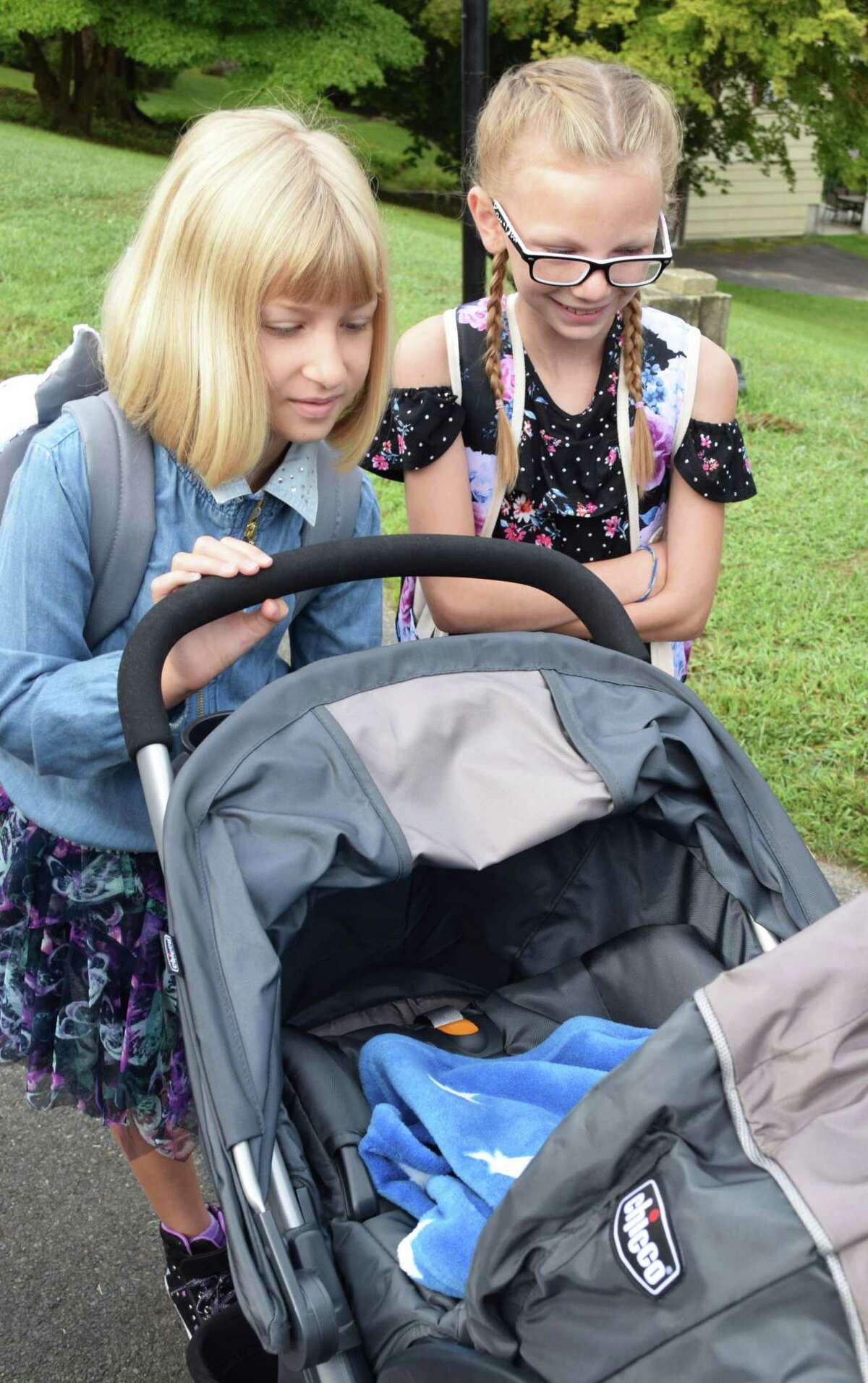Third grader Lily Bozek, left, debuts her brother, Dean, who is just a few days old, to fifth Makayla Gillette as they wait for the bus to take them to Sarah Noble Intermediate School.