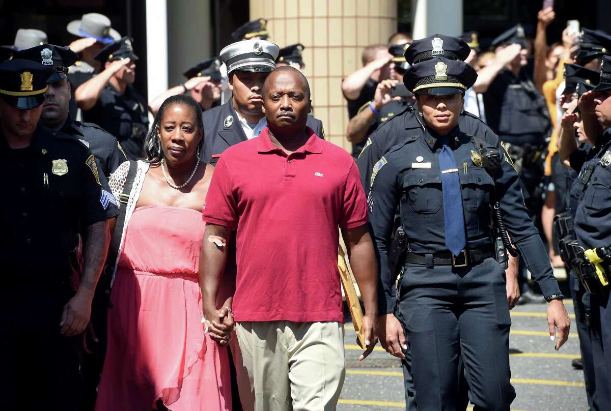 Members of the New Haven Police Department salute as Capt. Anthony Duff leaves Yale New Haven Hospital with his wife Aug. 22, a week after he was shot intervening in a shooting while off-duty.